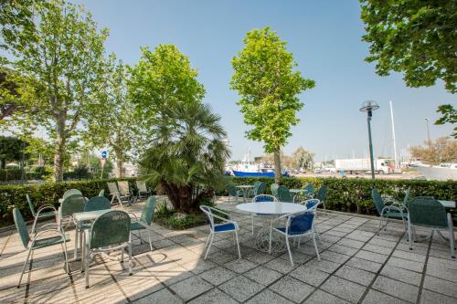 a patio with tables and chairs and trees at Hotel Baltic in Cesenatico