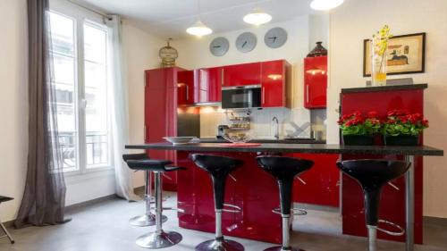 ジュアン・レ・パンにあるStylish White and Red Apartmentsのキッチン(赤いキャビネット、黒いカウンタースツール付)