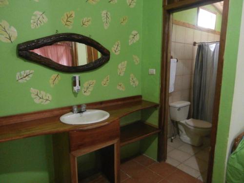 y baño con lavabo, espejo y aseo. en Hotel El Amanecer, en Monteverde