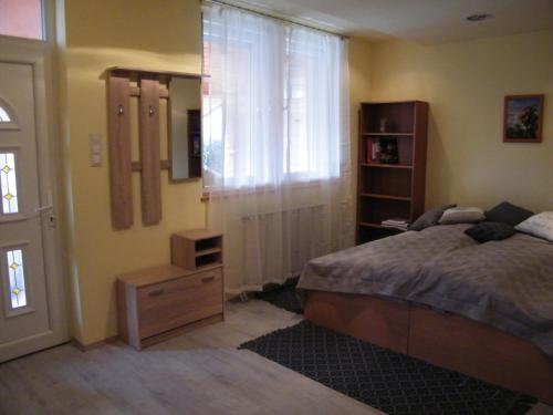 a bedroom with a bed and a dresser and a window at Pál utcai Apartman Miskolc in Miskolc