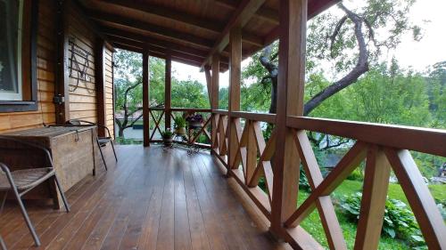 a porch of a wooden cabin with a tree at Country House Kosiv in Kosiv