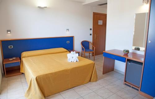 a bedroom with a bed with a yellow bedspread and a table at Hotel Smeraldo in Tortoreto Lido