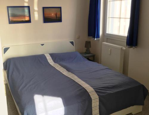 ein Schlafzimmer mit einem Bett mit einer blauen Decke in der Unterkunft Wohnen am Yachthafen in Ostseebad Karlshagen