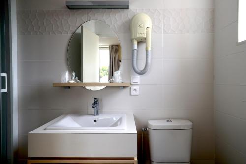 La salle de bains est pourvue d'un lavabo, d'un miroir et de toilettes. dans l'établissement Hôtel Miléade de la Plage - Binic, à Binic