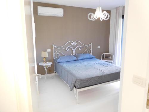 a bedroom with a bed with blue pillows and a chandelier at Appartamento Tilatti in Grado