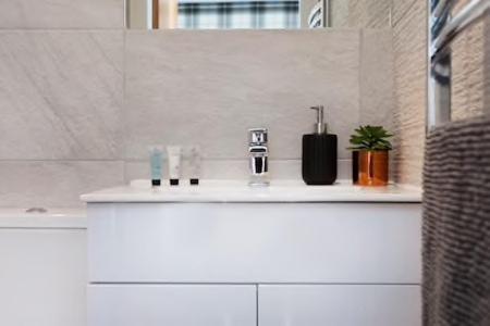 a white bathroom with a sink and a window at The Woodpecker Snug in Nottingham