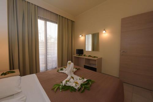 ein Hotelzimmer mit einem Bett mit Blumen darauf in der Unterkunft Santa Helena Hotel in Ialyssos