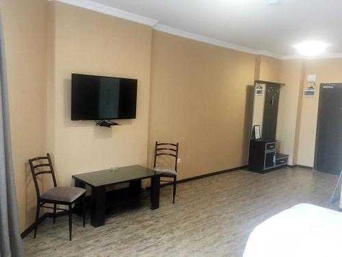 a room with a table and chairs and a television on the wall at Pirosmani Mini Hotel in Batumi