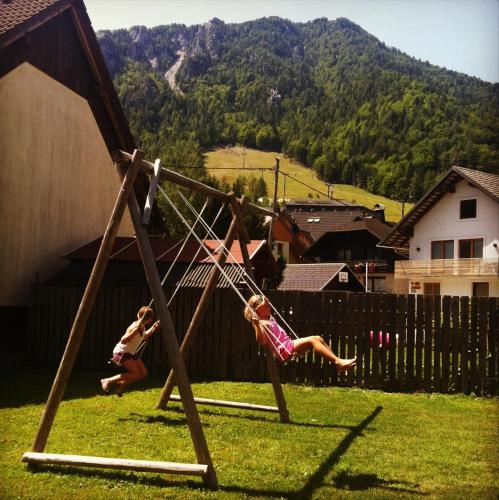 two children playing on a swing set in a yard at House Neza in Kranjska Gora