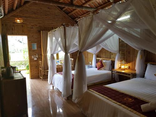 a bedroom with two beds with white drapes at Tam Coc Horizon Bungalow in Ninh Binh