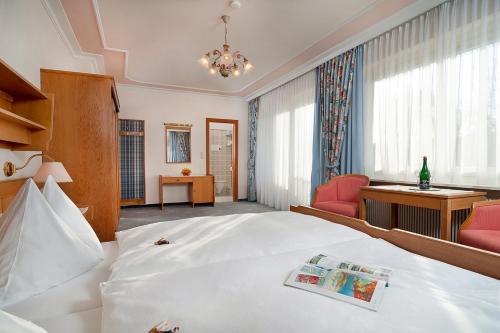 a hotel room with a large white bed and a desk at Gästehaus Fertschey in Velden am Wörthersee