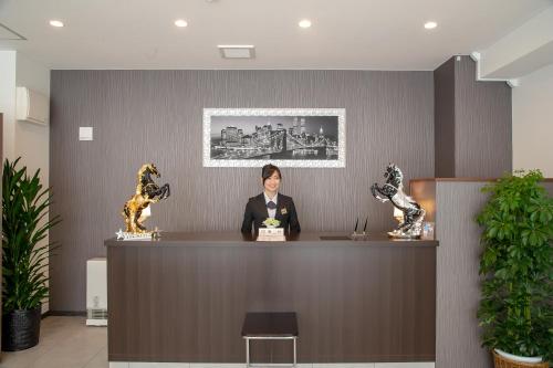a woman is sitting at a counter in a lobby at Condominium Stella Site in Hakodate