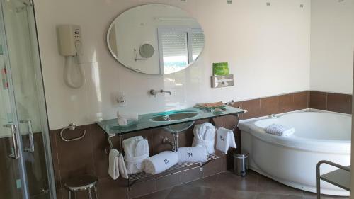 a bathroom with a sink and a tub and a mirror at Private Hôtel - Adults Only in Porto-Vecchio