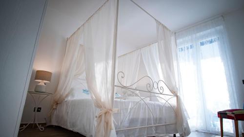 a white canopy bed in a bedroom with a window at Le Casette di Ponente in Milazzo