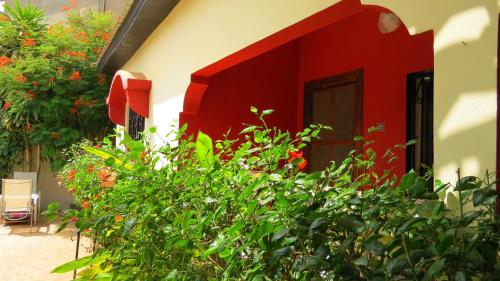 a red and white house with plants in front of it at Kingfishers Apartments in Bijilo