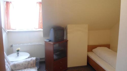 um pequeno quarto com uma cama e uma televisão num armário em Hotel Krone em Gößweinstein