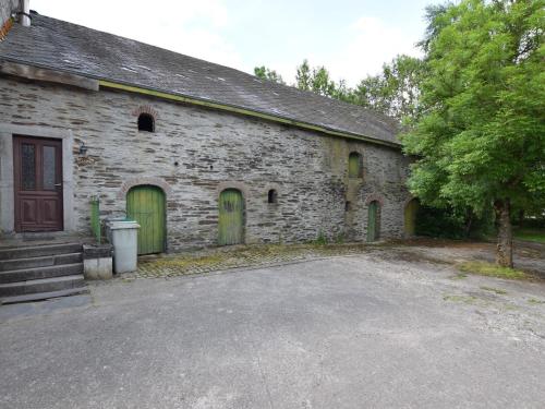 un antiguo edificio de piedra con puertas verdes y entrada en Characteristic Arden farmhouse with Valley views, en Tenneville