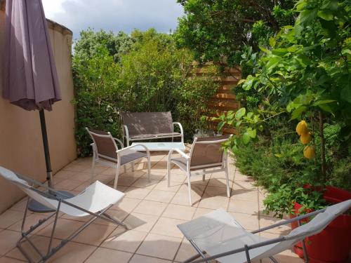 a patio with chairs and a table and an umbrella at Private Hôtel - Adults Only in Porto-Vecchio