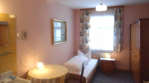 a bedroom with a bed and a table and a window at Hotel Krone in Gößweinstein