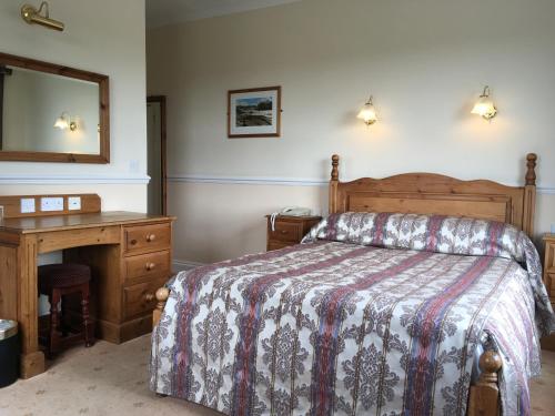 a bedroom with a bed and a desk and a mirror at Beggars Reach Hotel in Pembroke Dock