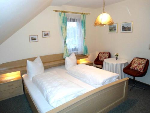 a bed in a room with two chairs and a table at Hotel Krone in Gößweinstein