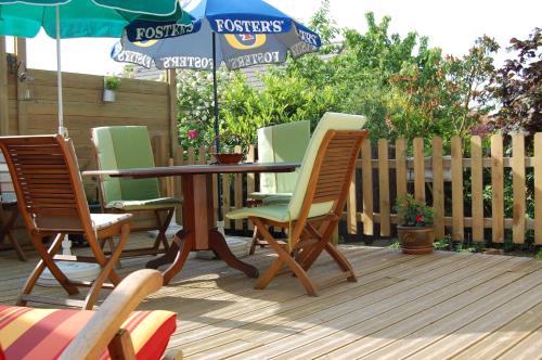 a table with chairs and an umbrella on a deck at Couette Et Cafe Crème in Le Coudray