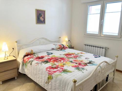 a bedroom with a white bed with a floral bedspread at Casa Pola in Grado