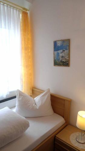 a bed with a pillow sitting next to a window at Hotel Krone in Gößweinstein