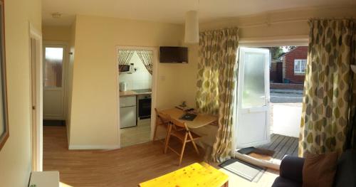 a kitchen and a living room with a table and a door at Beach Cottage in Jaywick Sands