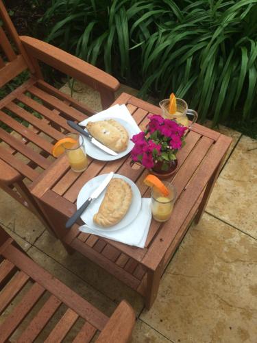 a picnic table with a plate of bread and orange juice at The garden apartment in St Ives