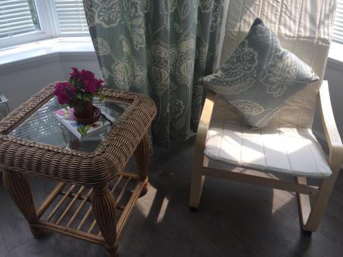 a wicker chair and a table with a vase of flowers at The garden apartment in St Ives