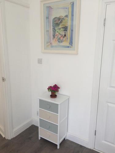 a white dresser with a painting on a wall at The garden apartment in St Ives