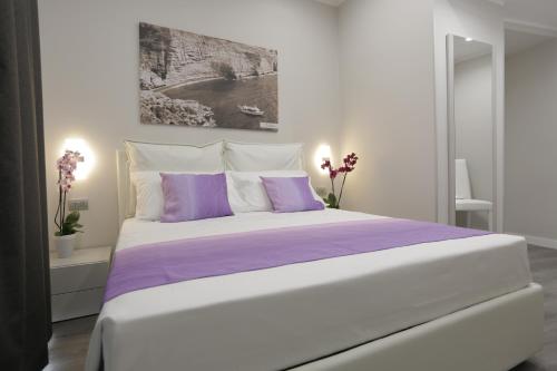 a white bedroom with a large bed with purple sheets at Sunset Tropea in Tropea