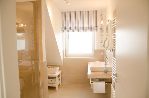 シュタインフーデにあるHus Achterliekのバスルーム(洗面台、鏡、窓付)