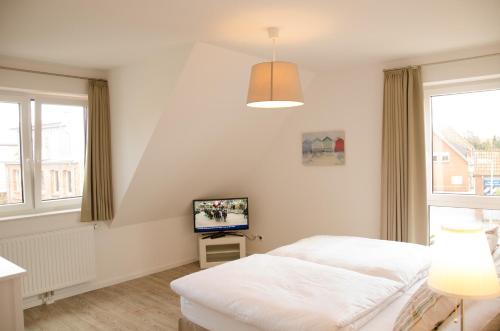 シュタインフーデにあるHus Achterliekの白いベッドルーム(ベッド1台、テレビ付)