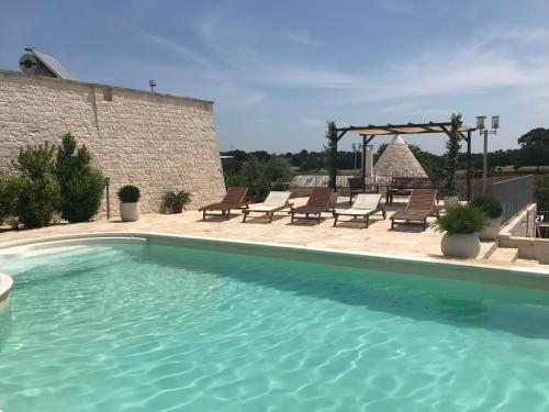 a swimming pool with chairs and a gazebo at Cappelluzzo in Cisternino