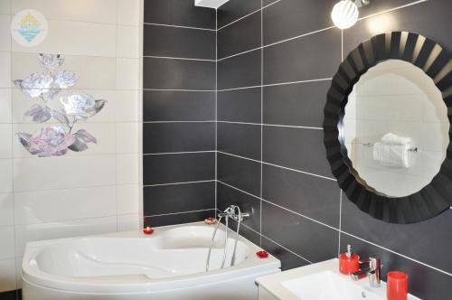 a bathroom with a tub and a sink and a mirror at Antos Deluxe Apartment in Constanţa