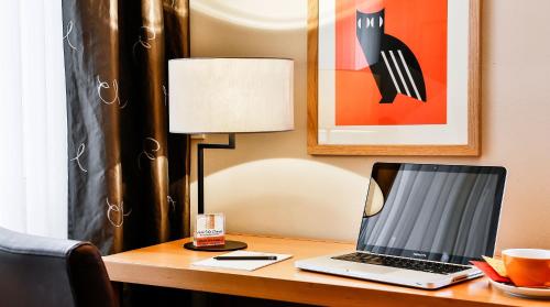 a laptop computer sitting on a desk with a lamp at BIO-Hotel Villa Orange in Frankfurt/Main