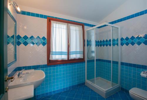 bagno piastrellato blu con lavandino e doccia di Maestrale BFlat - Klodge a Olbia
