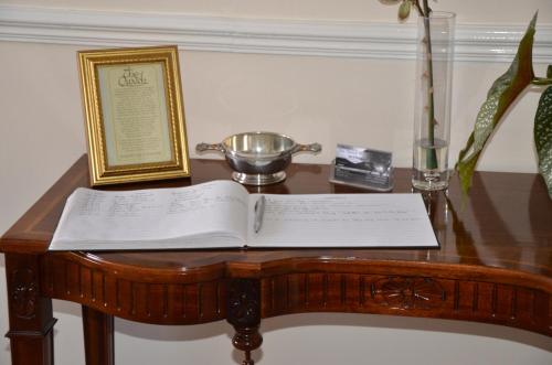 an open book on a wooden table with a bowl on it at The Quaich B&B in Inverness