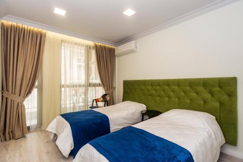 a bedroom with two beds and a green headboard at Vacation Apartment in Plovdiv