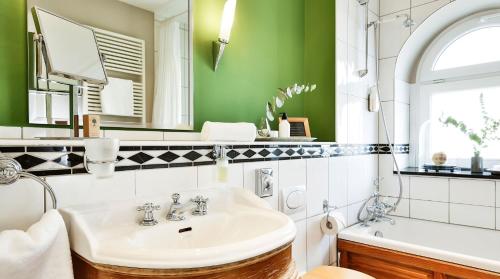 フランクフルト・アム・マインにあるBIO-Hotel Villa Orangeのバスルーム(シンク、鏡、バスタブ付)