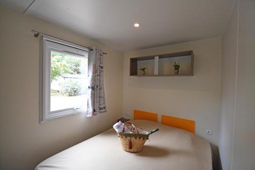 een slaapkamer met een bed met een raam en een mand bij Camping Le Sagone in Sagone