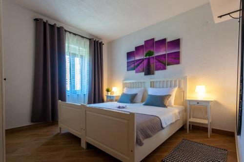 a bedroom with a bed with purple paintings on the wall at Apartment Placido Krk in Krk