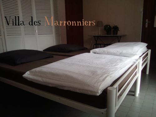 2 camas en un dormitorio con sábanas y almohadas blancas en Villa Des Marronniers, en Mirande