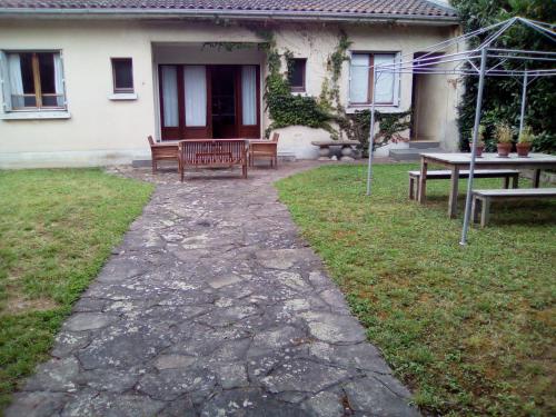 une terrasse avec des bancs et une table en face d'une maison dans l'établissement Villa Des Marronniers, à Mirande