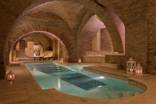 an indoor swimming pool in a building with a brick wall at Sina Brufani in Perugia