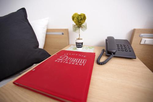 a red book on a desk with a phone at Dream Hotel in Velika Gorica