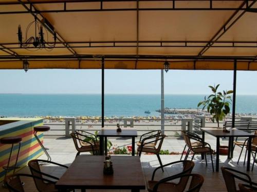 ein Restaurant mit Tischen und Stühlen und Meerblick in der Unterkunft Vila Maria in Eforie Nord