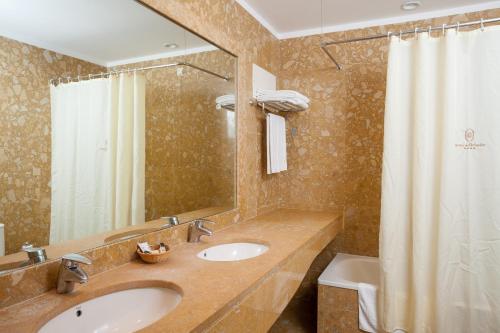 a bathroom with two sinks and a shower curtain at Hotel do Elevador in Braga
